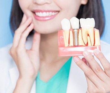 a dentist holding a model of a dental implant