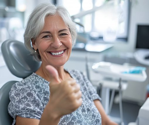 a dental patient smiling and giving a thumbs-up