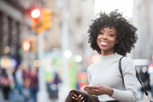 Woman smiling on her way to work as the city bustles behind her