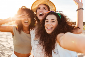 Three friends smiling and laughing on the beach